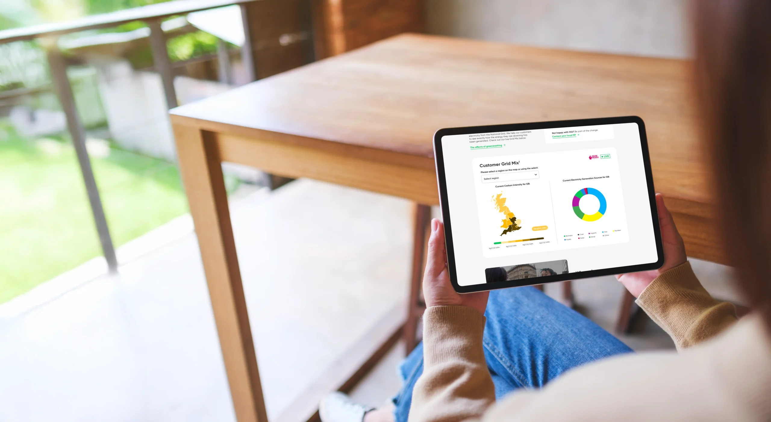 Person holding a tablet displaying Utilita Business's live carbon dashboard, promoting carbon transparency to customers.