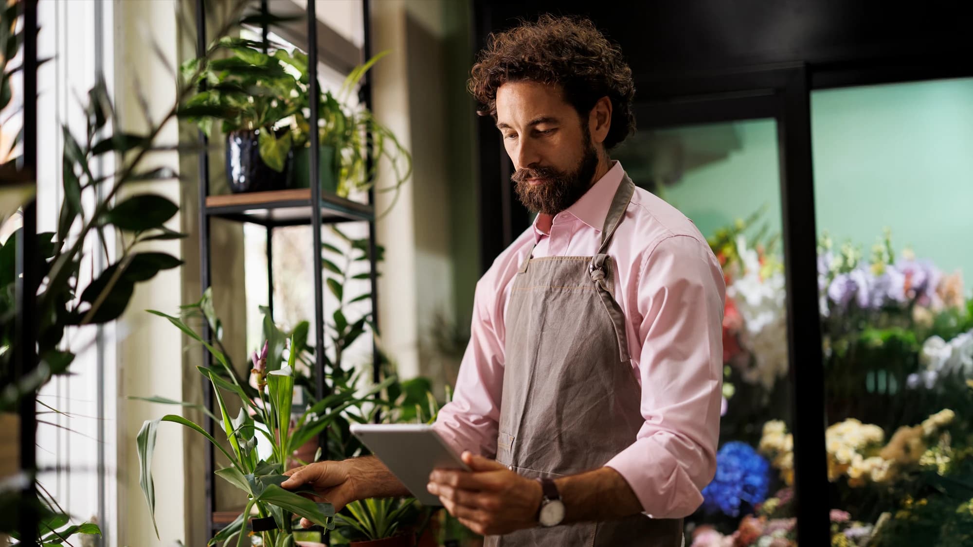 Man using a tablet to review his Transmission Network Use of System (TNUoS) charges applied to his business energy bills.