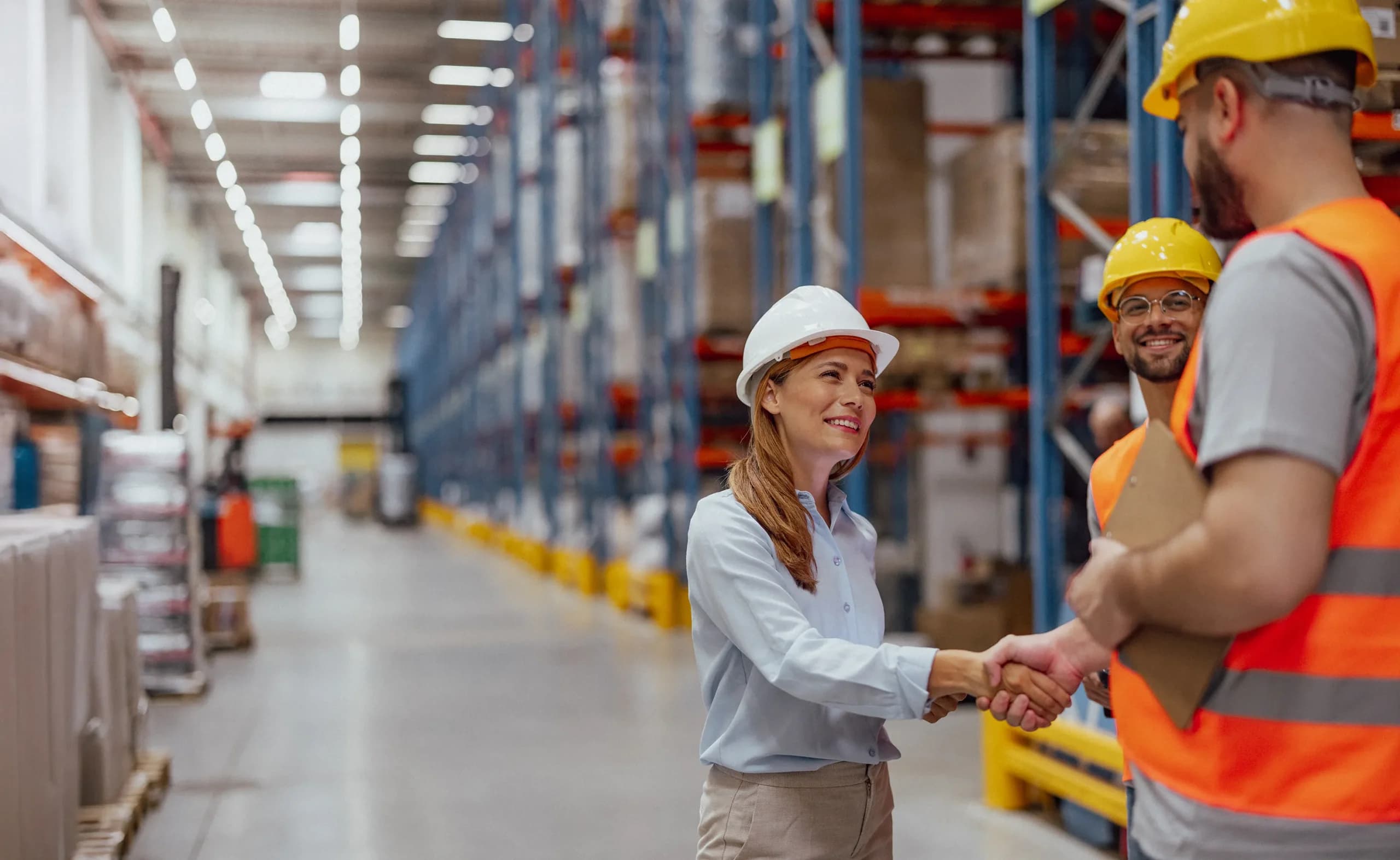 Woman in a factory shaking hands with two business development managers after switching her large business energy to Utilita.