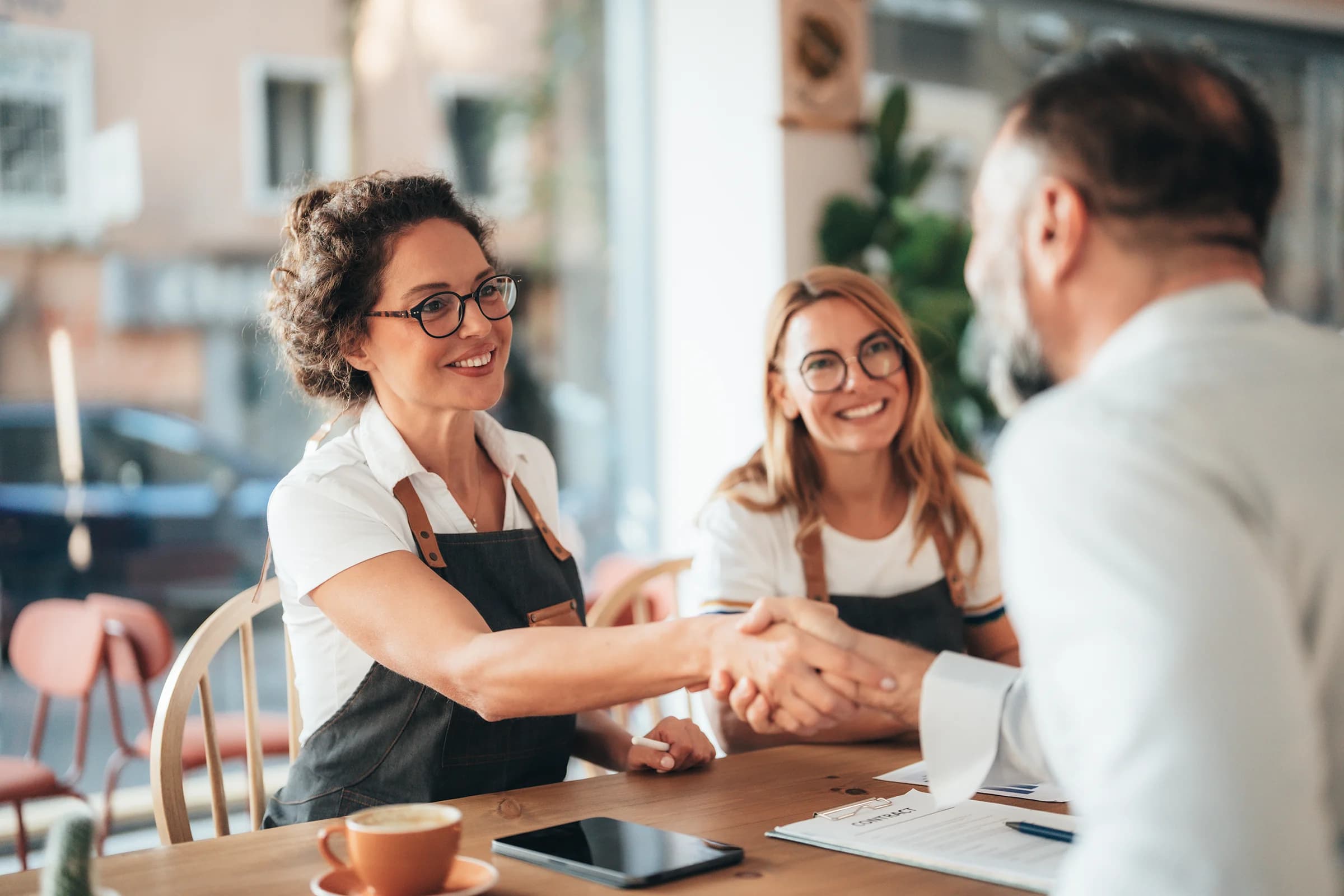 Two businesses owners shaking hands with their small business energy broker, representing Utilita's broker solutions.