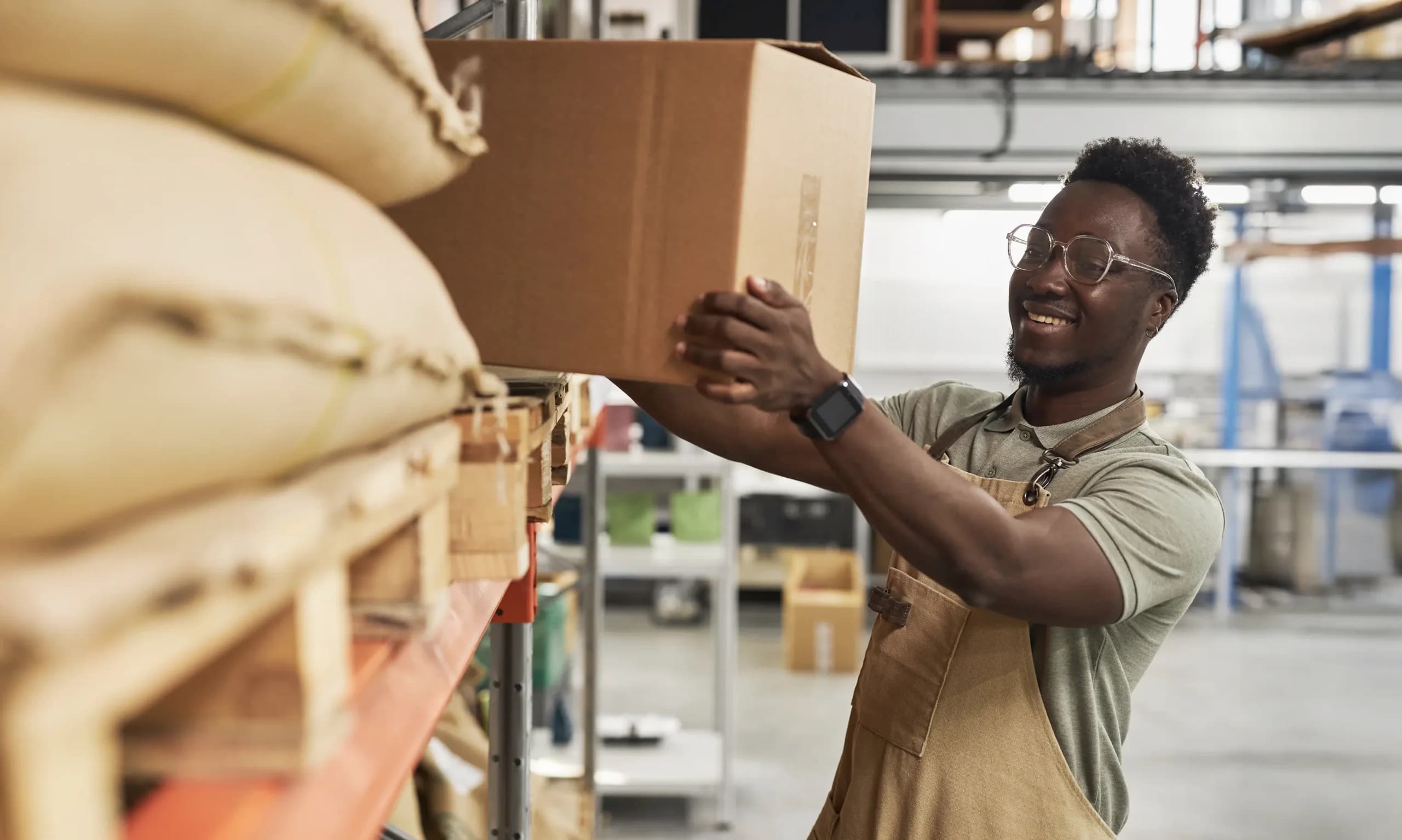 Fulfilment centre colleague picking up a cardboard box, showing how we supply business energy to logistics companies.